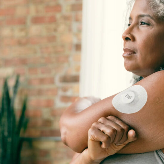 Overweight Black woman wearing a glucose sensor on her upper arm.