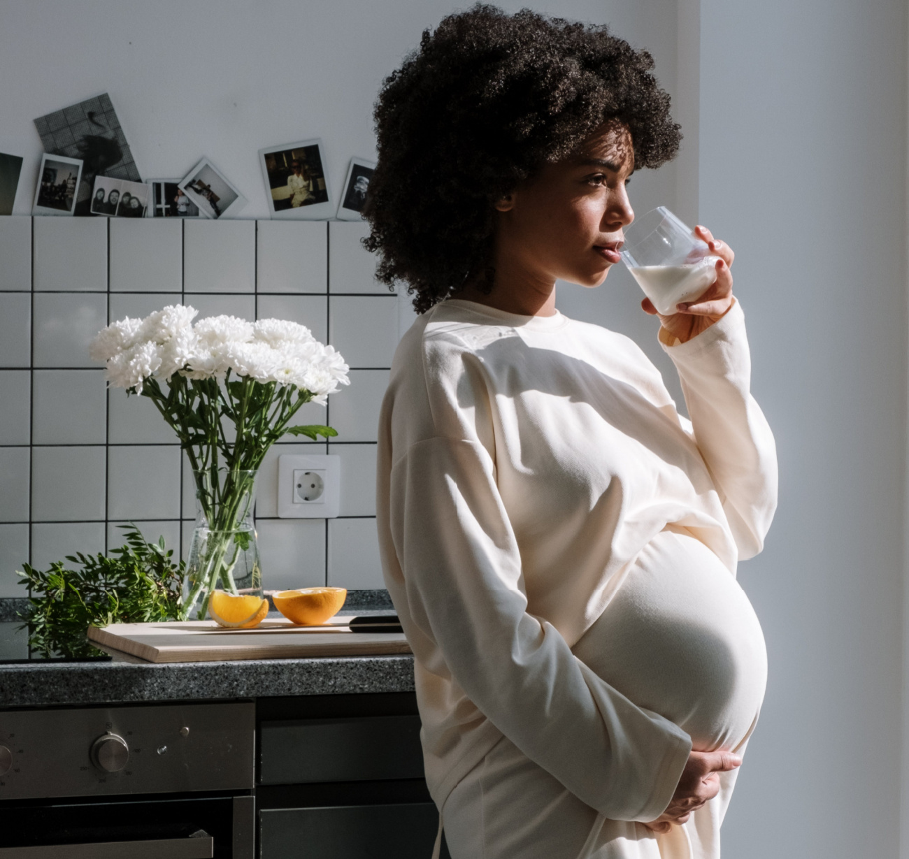 Pregnant young woman holding her baby belly and drinking a glass of water